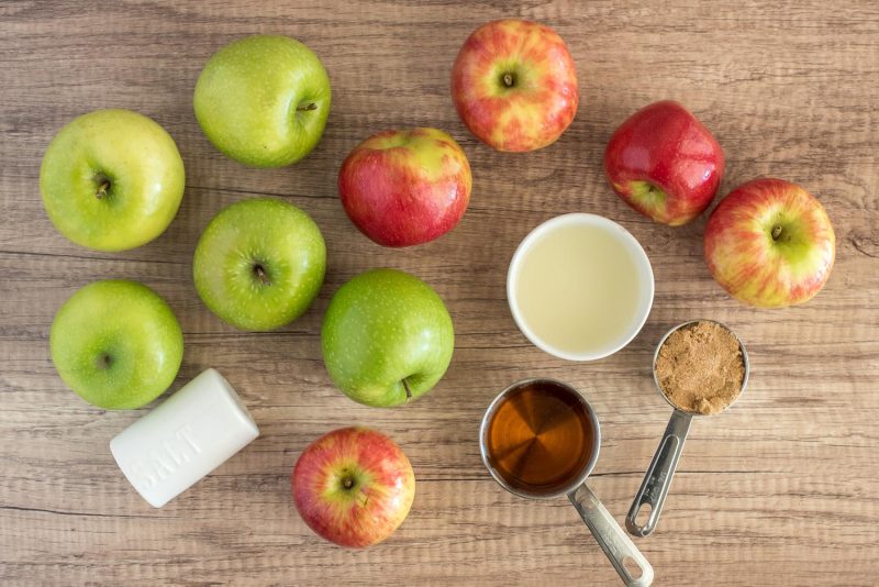 An overhead picture of ingredients for making Instant Pot apple butter, including a mix of red and green apples, salt, hard cider, and brown sugar.