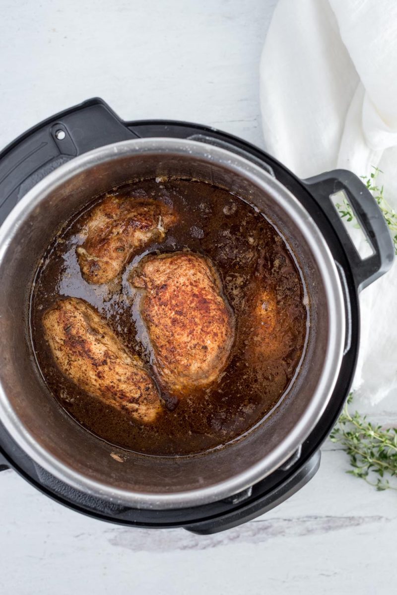 An overhead shot of the browned chicken inside the Instant Pot prior to ccooking