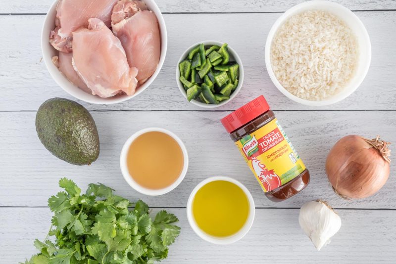Ingredients for making Instant Pot asopao including chicken thighs, avocado, cilantro, oil, apple cider vinegar, Caldo de Tomato, garlic, onion, pablano pepper, and cooked rice.