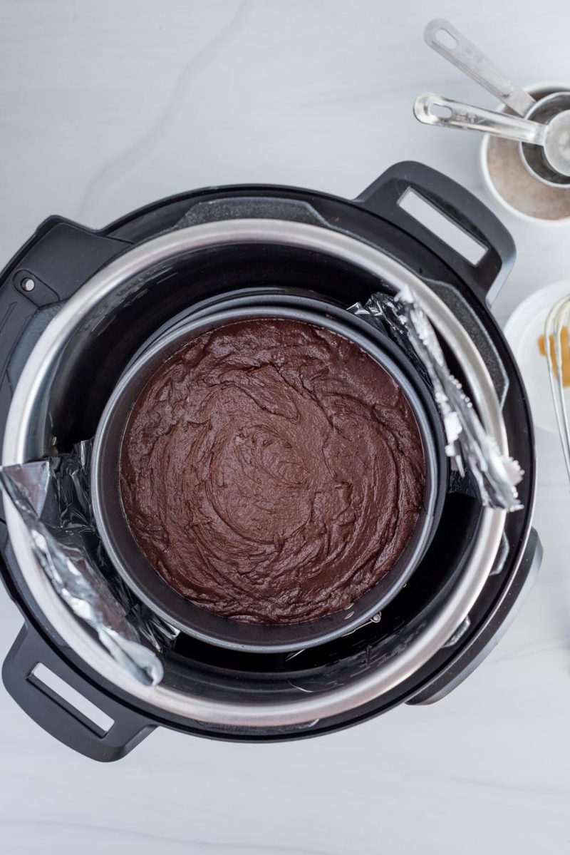 An overhead picture of the brownie crust in the bottom of the spring form pan for making a Black Forest cheesecake.