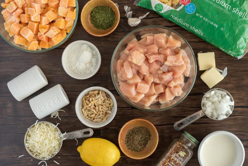 Ingredients for Instant Pot butternut squash pasta, including, chicken, frozen butternut squash, slivers almost, shell pasta, mozzarella, lemon, butter, corn starch, and spices.