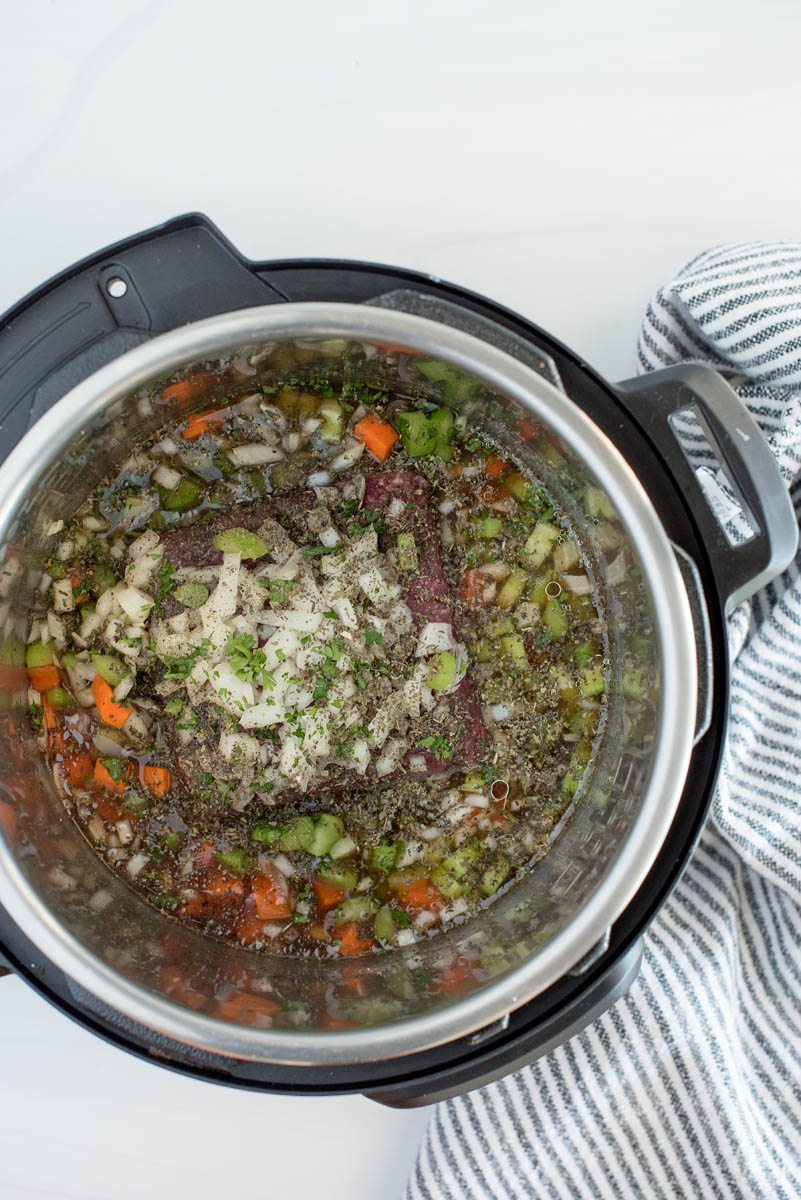 Meat, veggies, and spices added to the Instant Pot to cook cheeseburger soup.