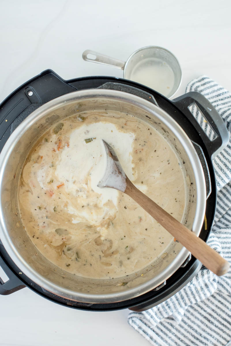 Adding cream to the Instant Pot to finish cheeseburger soup.
