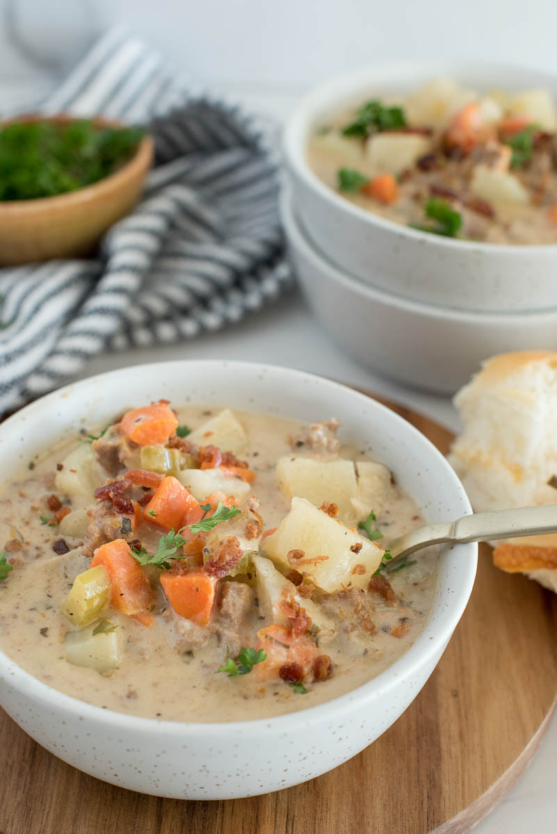 Close up on Instant Pot cheeseburger soup with chunky potatoes and carrots, topped with fresh parsley and crumbled bacon.