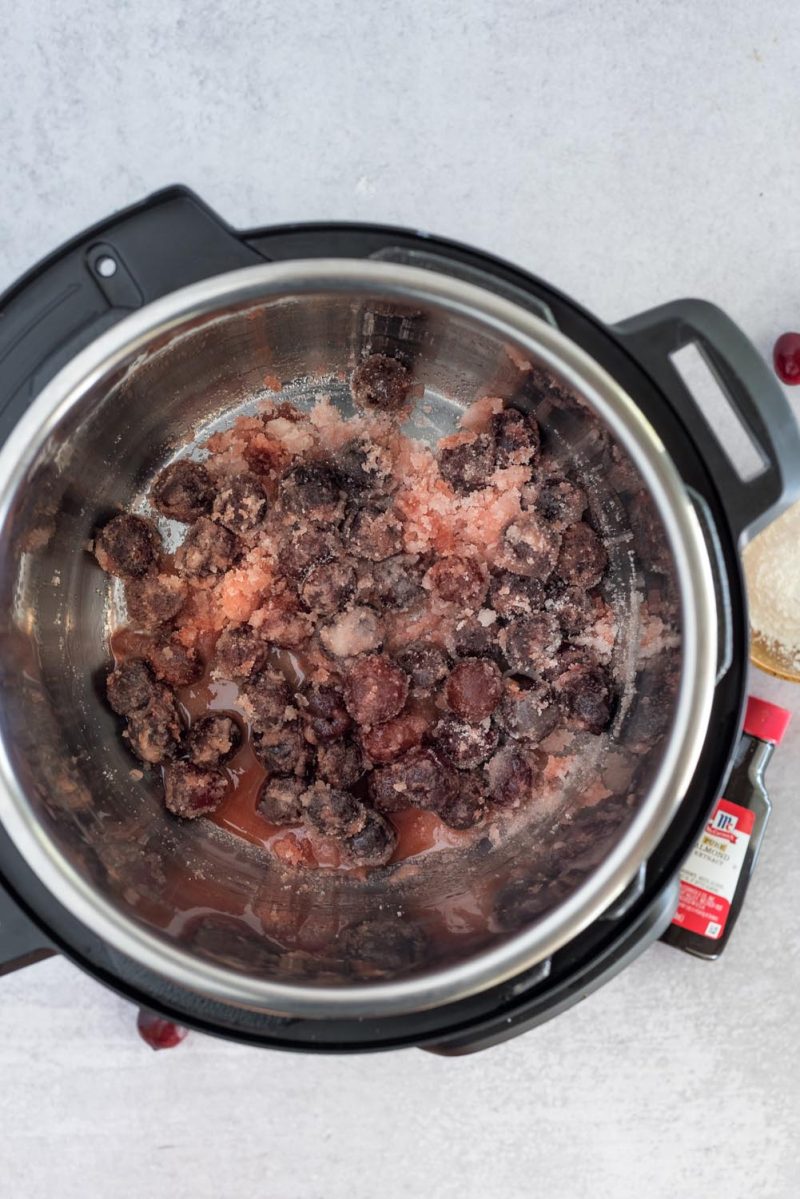 An overhead shot of frozen cherries in the silver Instant Pot cooking pot