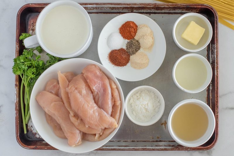 Ingredients for Instant Pot chicken lazone including, chicken tenderloins, chicken broth, heavy cream, spices, butter, oil, and corn starch.
