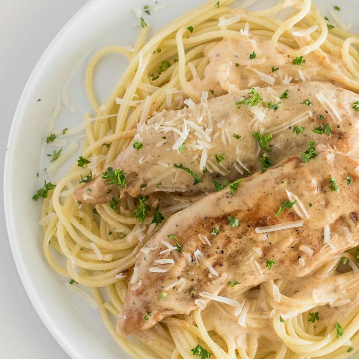 Overhead picture of chicken lazone served on noodles with a cream sauce and fresh parsley.
