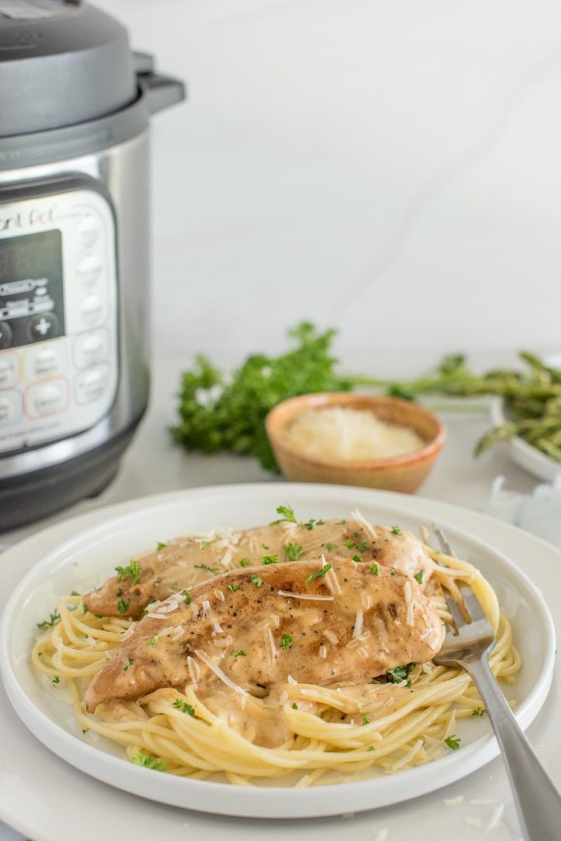 Chicken lazone served on noodles with a cream sauce and fresh parsley, placed in front of an Instant Pot.