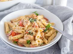A white bowl with Instant Pot chicken bacon penne topped with fresh parsley and cheese.