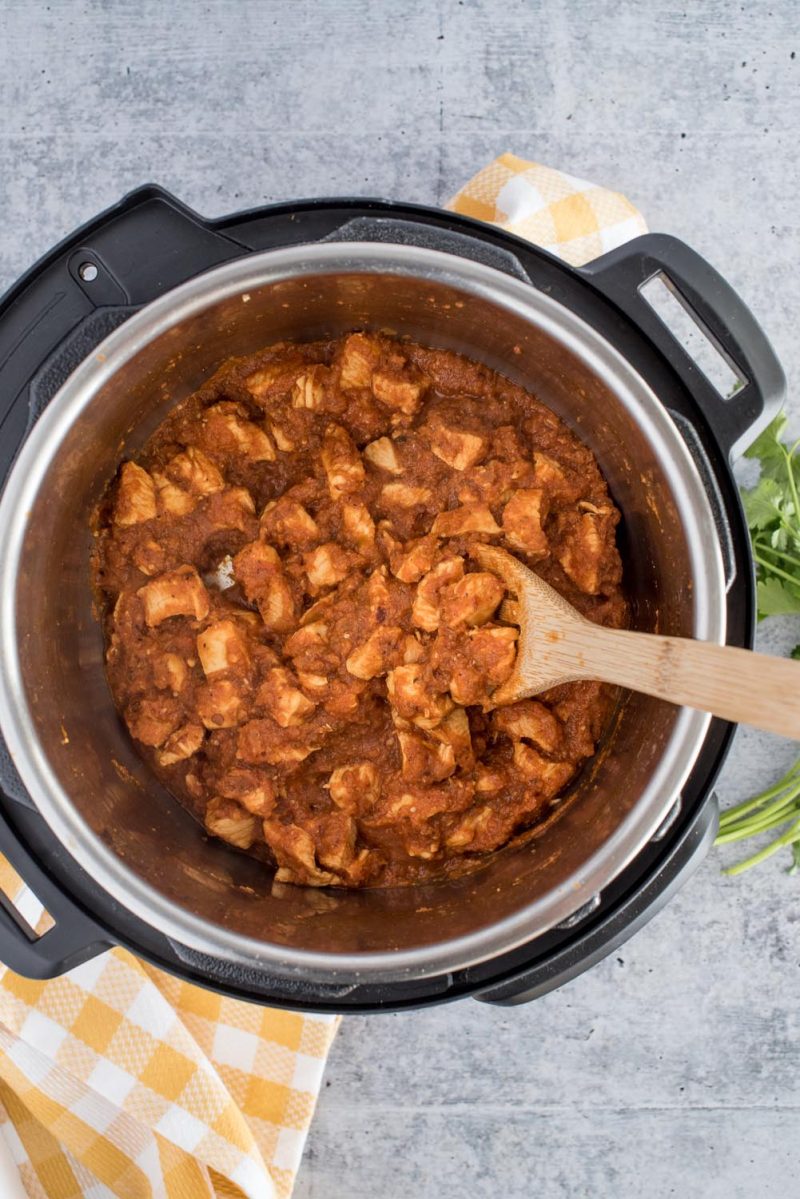 An overhead shot looking into a pot of Instant Pot, with diced chicken added to the sauce.