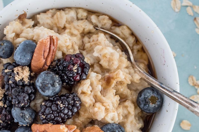 A close up picture of Instant Pot oatmeal served in a white bowl and topped with blackberries, blueberries and pecans.