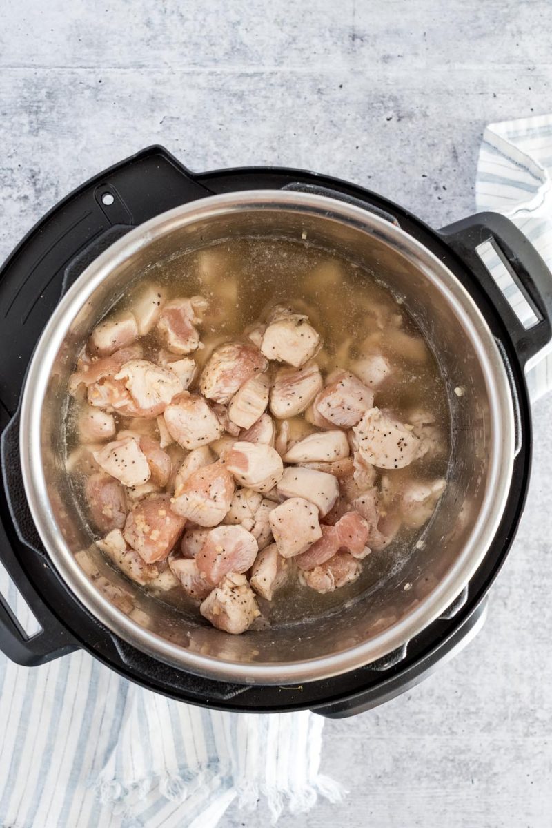 Diced chicken that had been browned in an Instant Pot, with chicken broth, ready to be cooked.