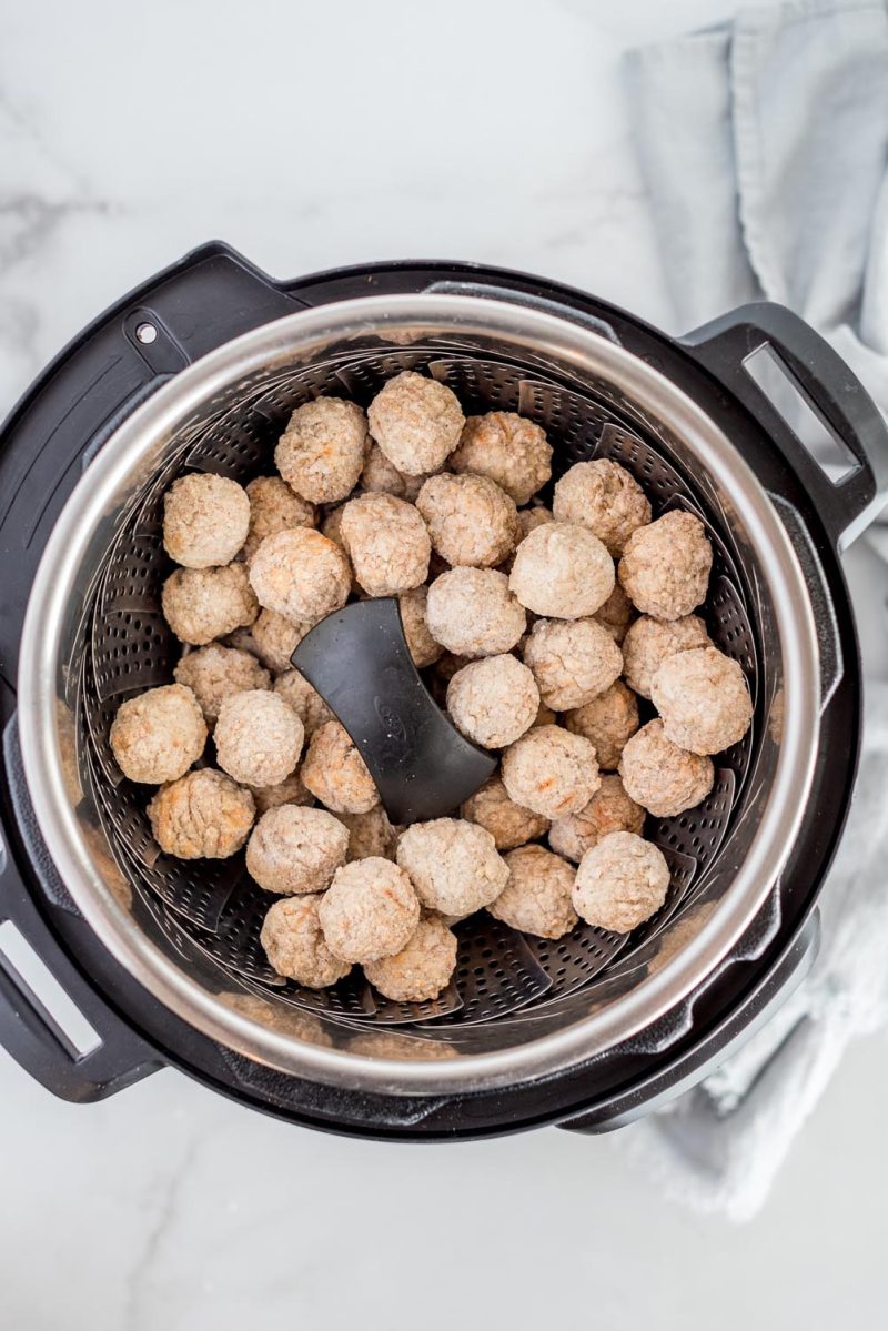 Frozen meatballs on in a basket ready to be cooked in an Instant Pot.