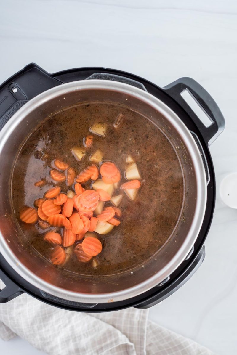 Overhead picture of Guinness stew cooking in an Instant Pot and adding potatoes and carrots.