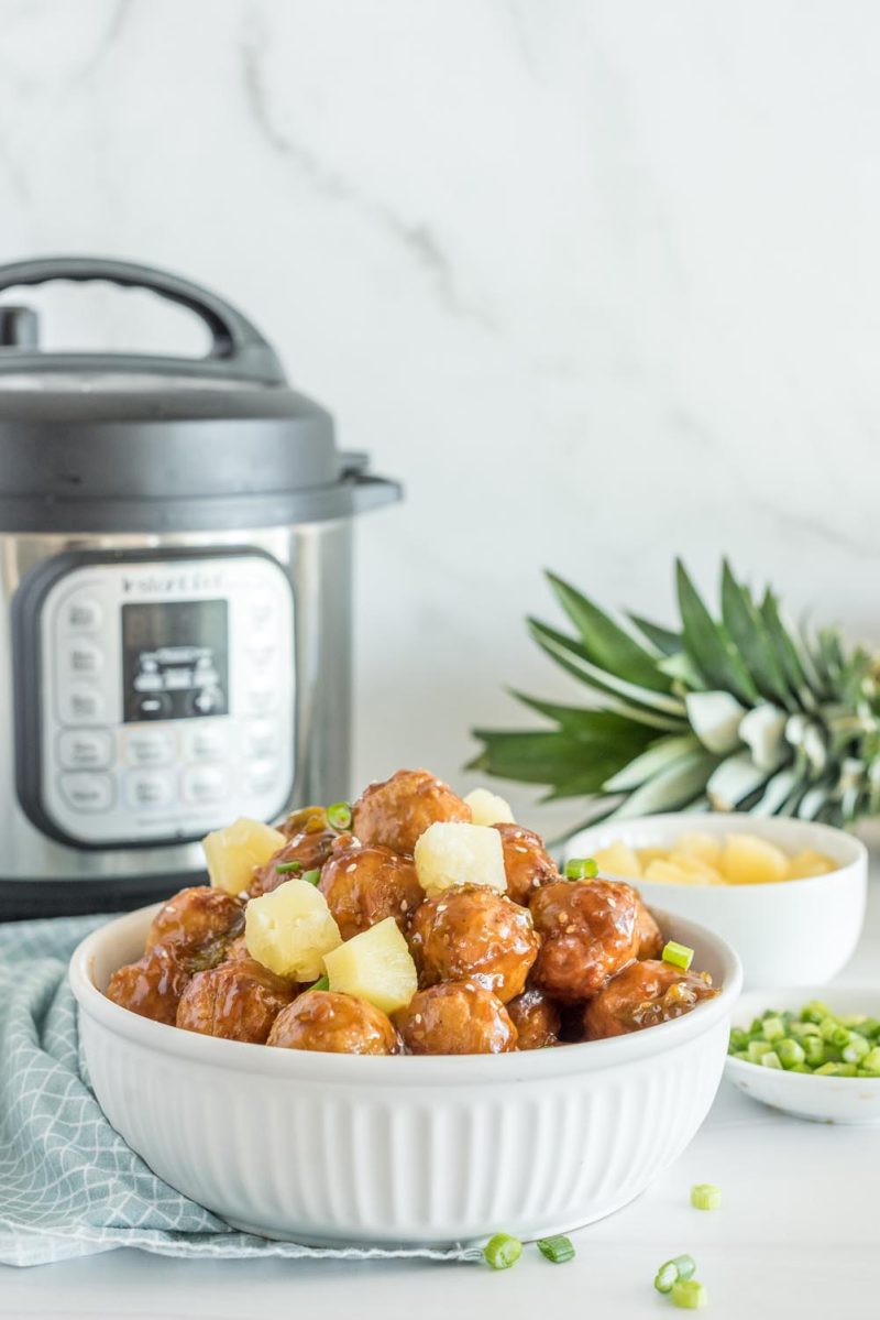 A white serving bowl with Hawaiian meatballs ready to eat, and placed in front of an Instant Pot.