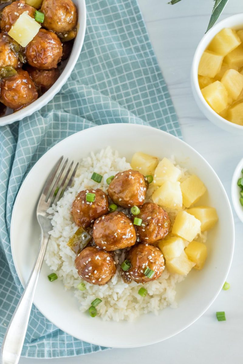 Overhead picture of Instant Pot Hawaiian meatballs served over white rice, with sesame seeds, green onions, and pineapple.