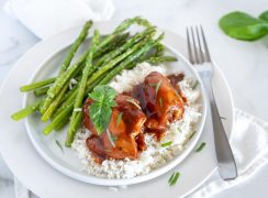 Instant Pot honey garlic chicken plated on white rice and asparagus, topped with fresh parsley.