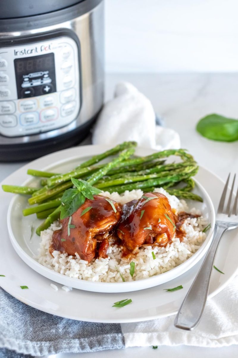 Honey garlic chicken plated with white rice and asparagus and placed in front of an Instant Pot.