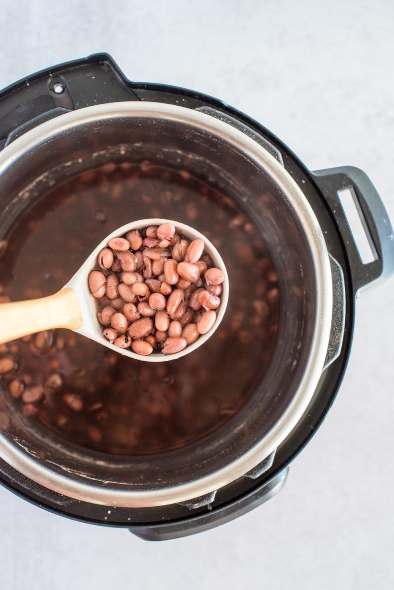 A ladle with kidney beans over an Instant Pot with cooked kidney beans inside.