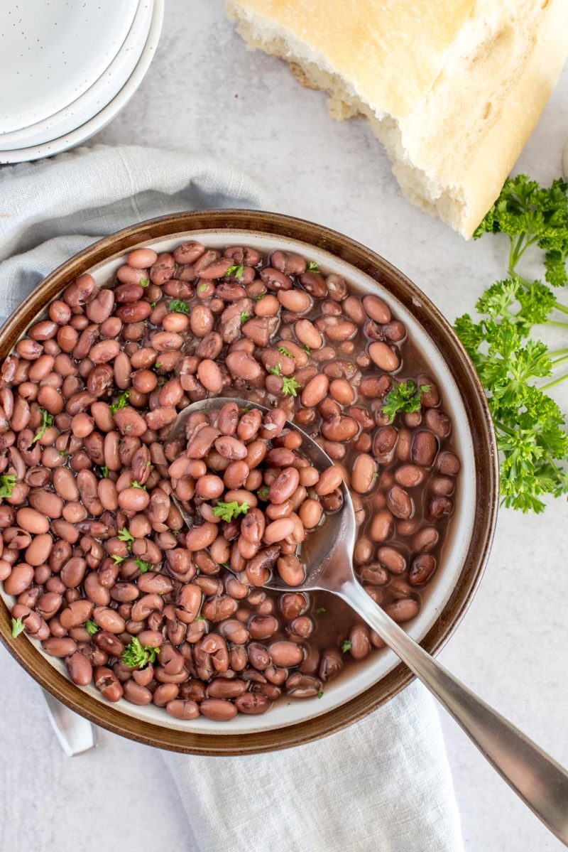 Overhead picture of a bowl of Instant Pot kidney beans, topped with fresh parsley with a spoon in the bowl.