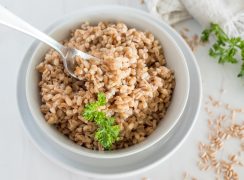 Instant Pot farro in a white bowl with a fresh sprig of parsley.