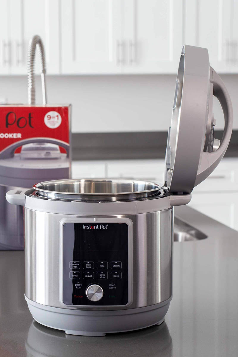 Instant Pot Duo Plus Whisper Quiet on a kitchen counter with the lid open and the box in the background.