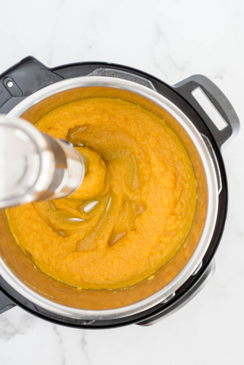Using an immersion blender to puree cooked pumpkin in an Instant Pot.
