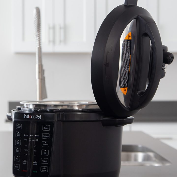 A profile picture of the Instant Pot Rio with the black exterior and the lid open and placed in the side fins to hold it while sautéing or serving.