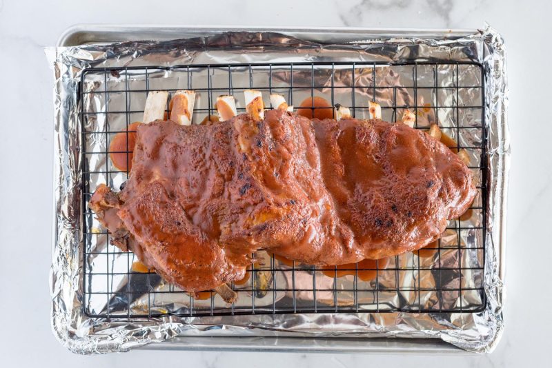 An overhead picture of Memphis style ribs that were cooked in an Instant Pot, smothered with sauce on a pan after being finished in the oven.