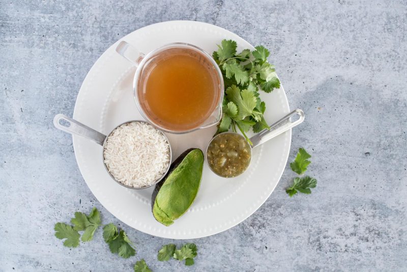 Ingredients for Instant Pot green rice including green salsa, avocado, rice, chicken broth, and cilantro