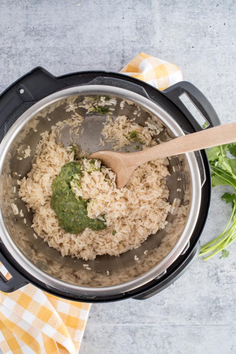 Adding green salsa to the rice in an Instant Pot.