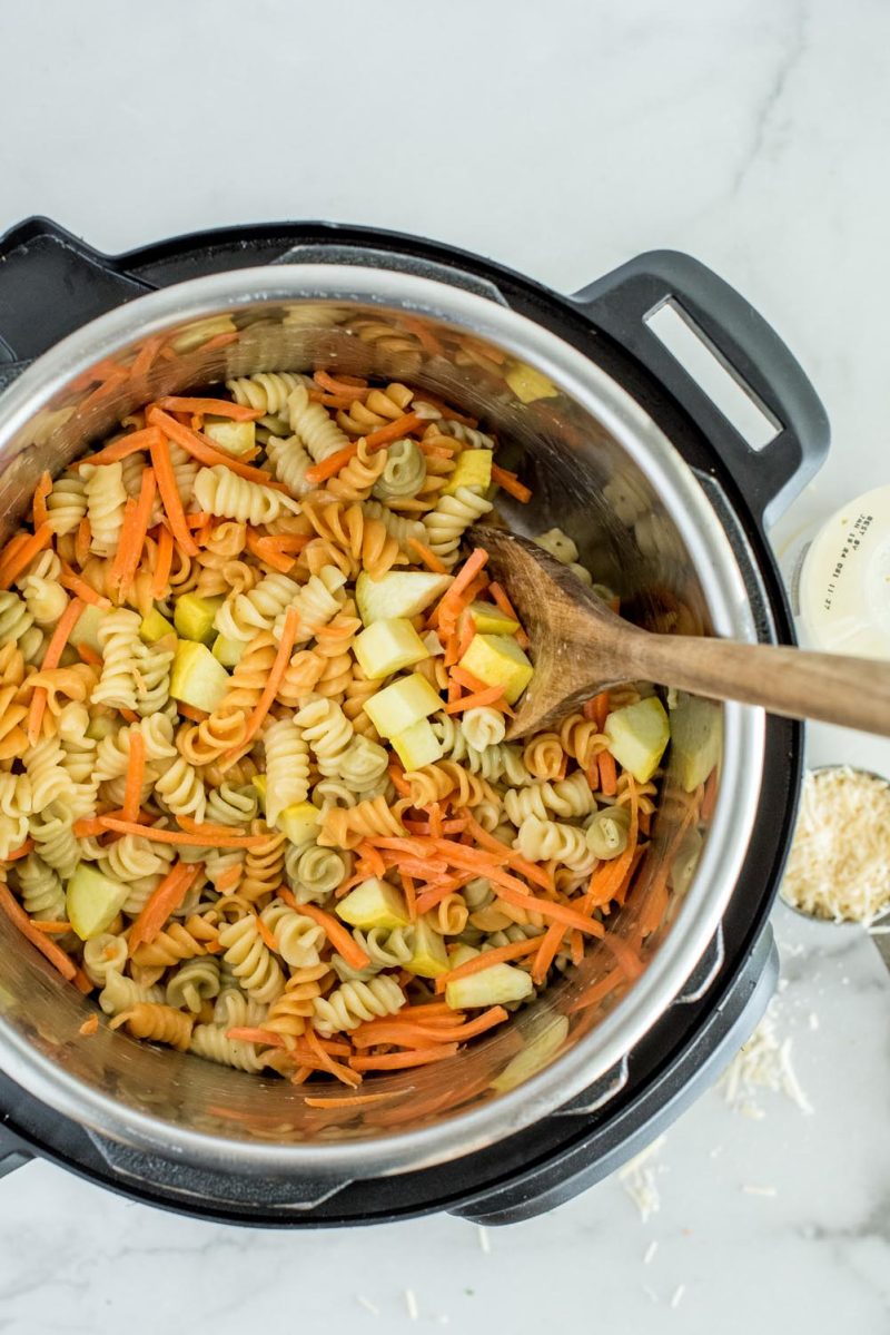 Cooked rotini noodles with yellow squash and match stick carrots in an Instant Pot to make pasta salad.