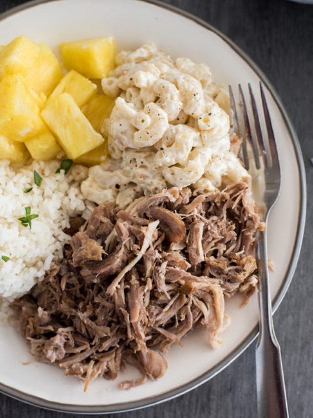 a tight-cropped shot of  a white plate filled with Kalua Pork, macaroni salad, rice, and fresh-cut pineapple