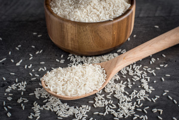 A wooden bowl full of white rice, ready to cook in the pressure cooker