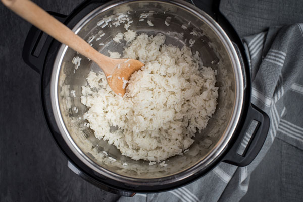 Pressure Cooker White Rice cooked and fluffed by a wooden spoon inside the Instant Pot cooking pot