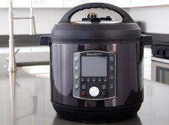 A close-up photo of a black Instant Pot Pro sitting on a dark gray countertop, with white cabinets in the background