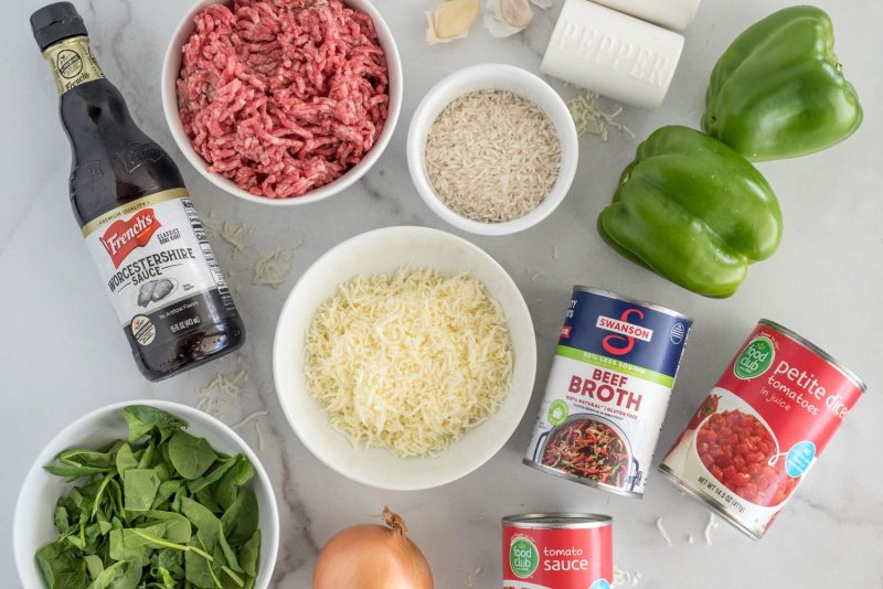 Ingredients for stuffed green pepper casserole, including green bell peppers, salt, pepper, panic, garlic, ground beef, Worcestershire sauce, chopped spinach, onion, tomato sauce, petite disced tomatoes, beef broth, and shredded cheese.