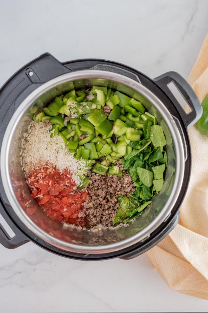 Ingredients added to an Instant Pot for making stuffed green pepper casserole.