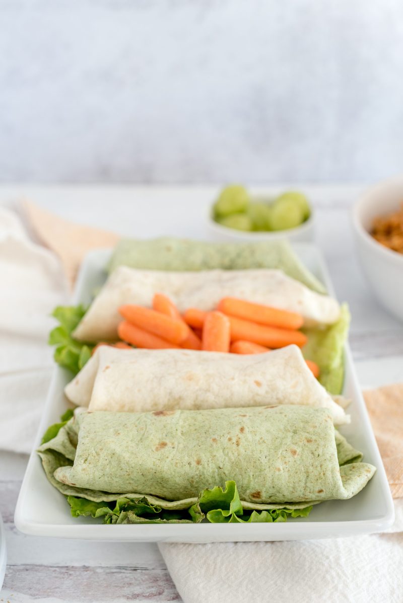 Thai chicken burritos with the filling made in an Insta pot, placed on a serving tray with lettuce and carrots.