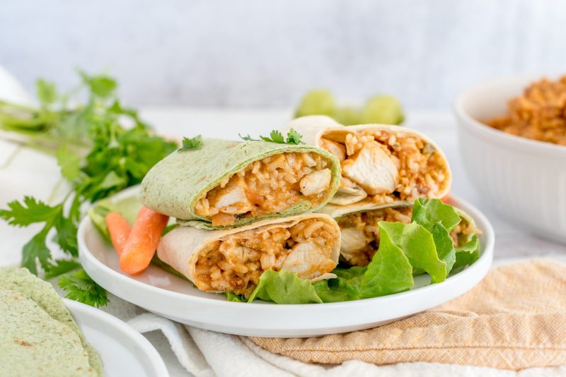 Instant Pot Thai chicken wraps stacked on a plate with lettuce and carrots