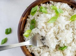 Overhead picture of a wooden bowl with Instant Pot white rice topped with green onion, with a fork in the bowl.
