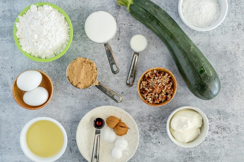 Ingredients for Instant Pot zucchini bread, including flour, eggs, oil, spices, brown sugar, sugar, pecans, sour cream, and zucchini.