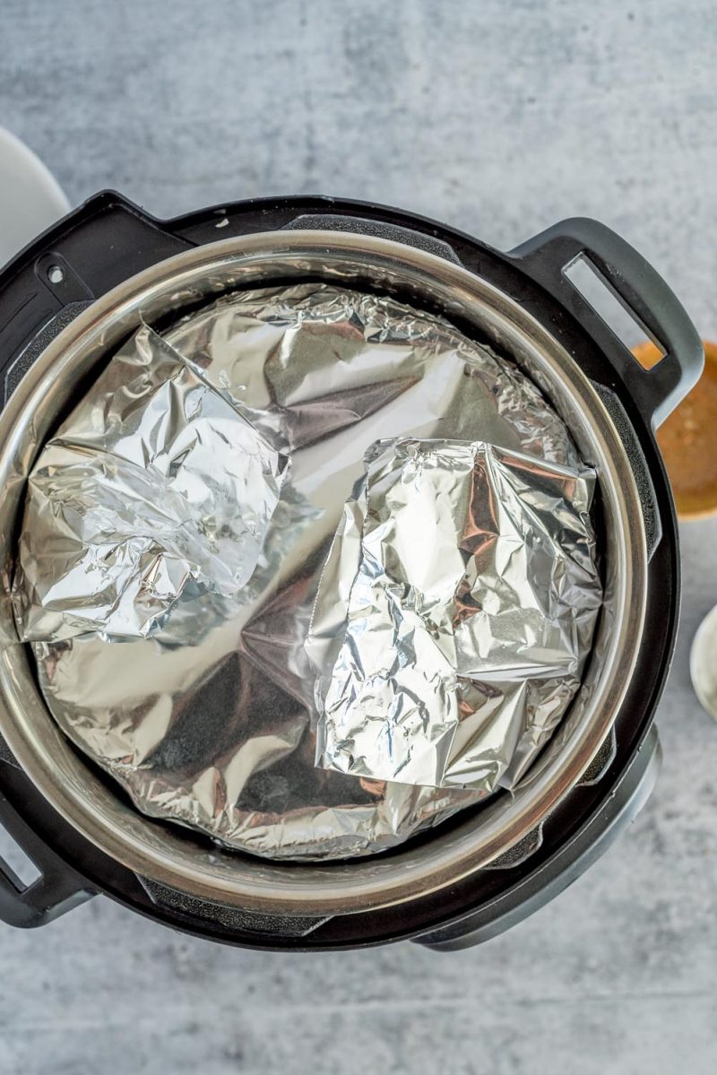 Overhead picture of a mini bundt pan covered with foil and placed inside an Instant Pot for making zucchini bread.